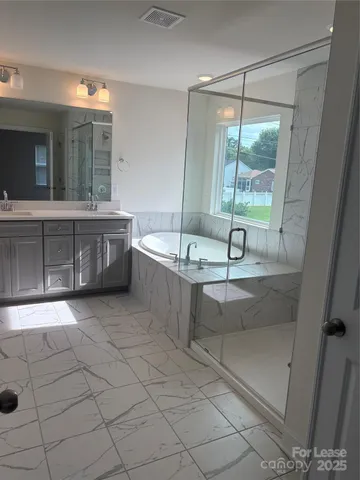 a spacious bathroom with a tub a sink and mirror