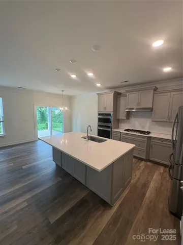 a large kitchen with a large counter top a sink stainless steel appliances and cabinets
