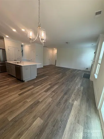a view of a room with kitchen island stainless steel appliances wooden floor and window