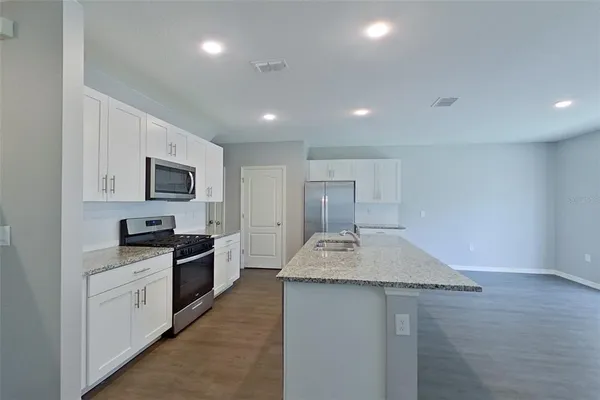 a kitchen with granite countertop a sink stainless steel appliances and white cabinets