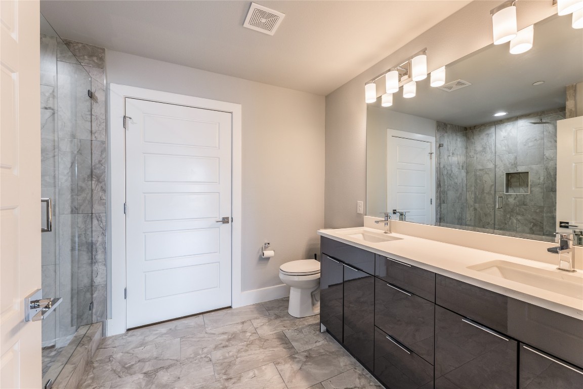 1417 Kramer Lane, Unit 9 Austin, TX 78758 - Photo 32 of 40 a bathroom with a double vanity sink a toilet and a mirror