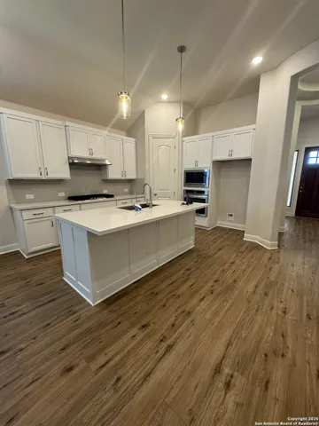 a large kitchen with stainless steel appliances a large counter top a stove a sink and a refrigerator