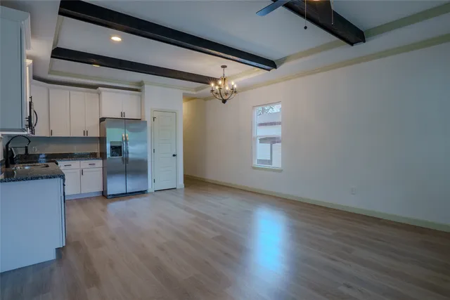 a view of empty room with wooden floor and electronic appliances