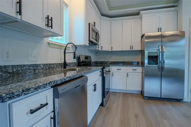 a kitchen with granite countertop a sink stainless steel appliances and cabinets