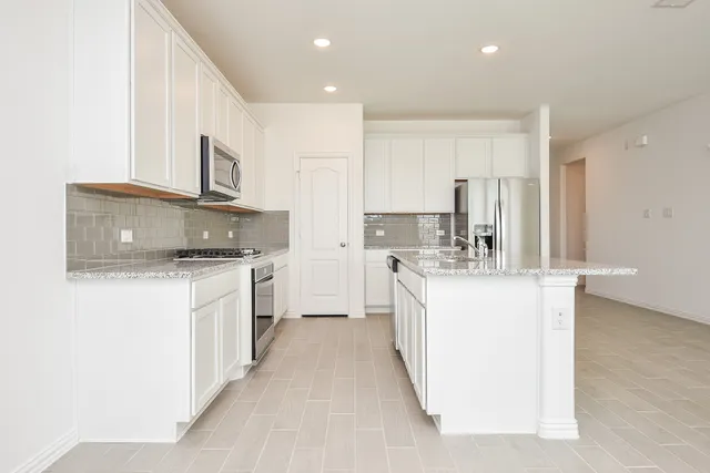 a kitchen with kitchen island sink stove and white cabinets