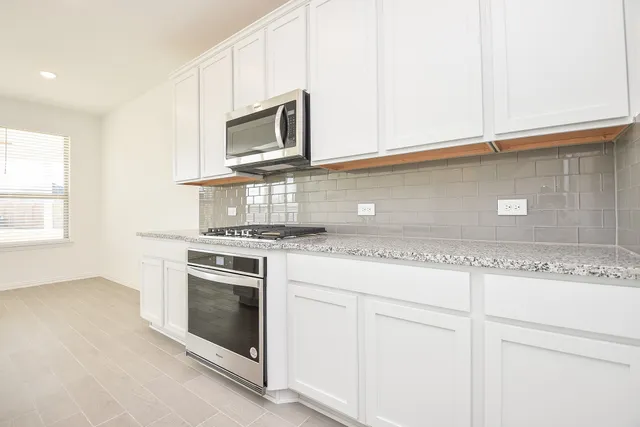 a kitchen with granite countertop white cabinets stainless steel appliances and sink