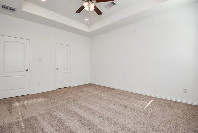 an empty room with a ceiling fan and carpet