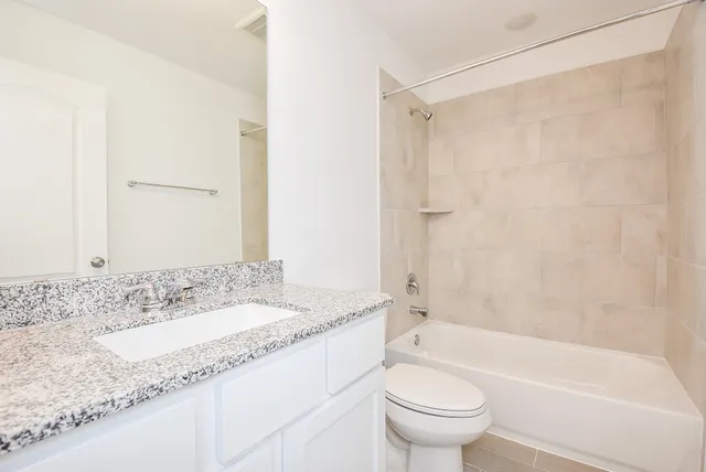 a bathroom with a granite countertop sink a toilet and shower