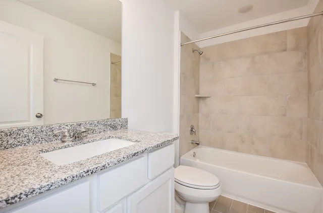 a bathroom with a granite countertop sink a toilet and shower
