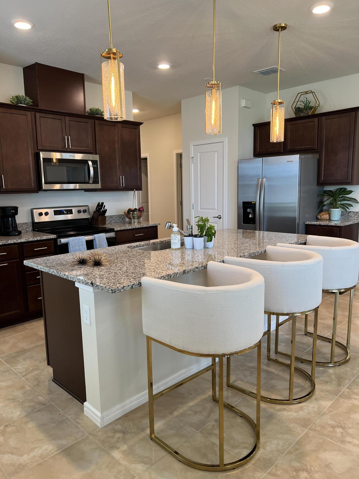 a kitchen with stainless steel appliances kitchen island granite countertop a sink a microwave and chairs