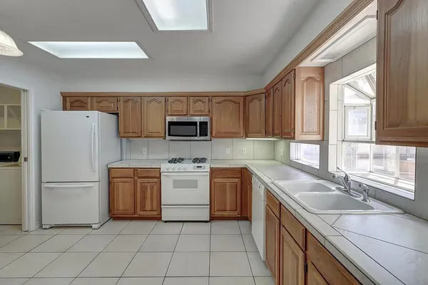 a kitchen with cabinets appliances a sink and a window