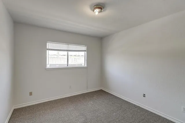 an empty room with windows and chandelier fan