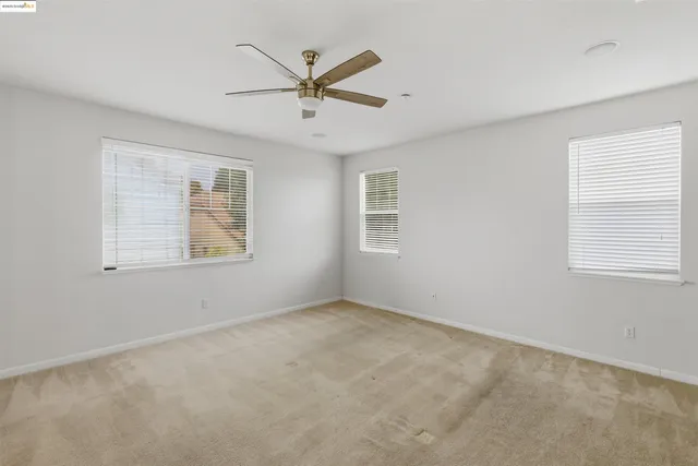 an empty room with closet and a ceiling fan