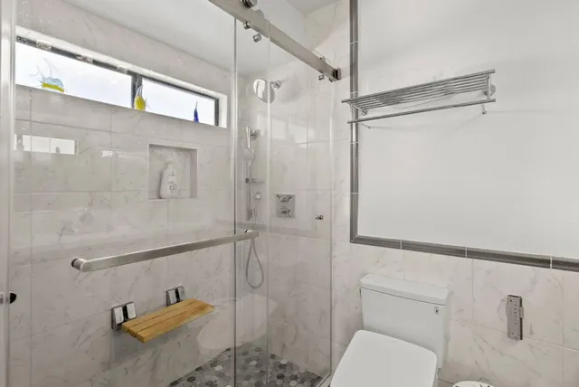 a bathroom with a granite countertop sink toilet a mirror and shower