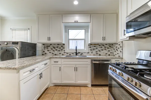 a kitchen with granite countertop a stove sink and cabinets