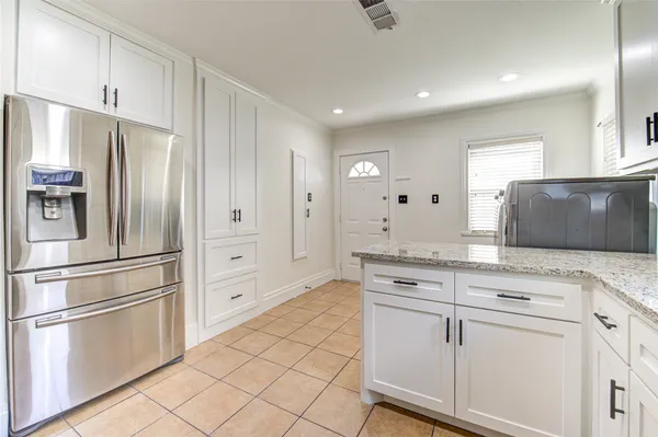a kitchen with white cabinets and refrigerator
