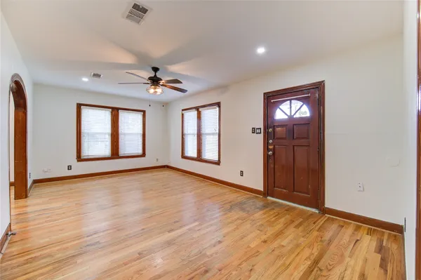a view of an empty room with a window and wooden floor