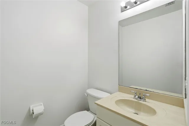 a bathroom with a toilet sink vanity and mirror