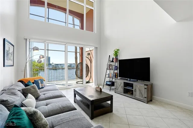 a living room with furniture a flat screen tv and a floor to ceiling window