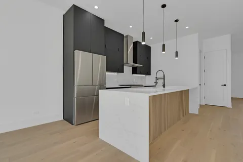 a kitchen with kitchen island a refrigerator and a sink