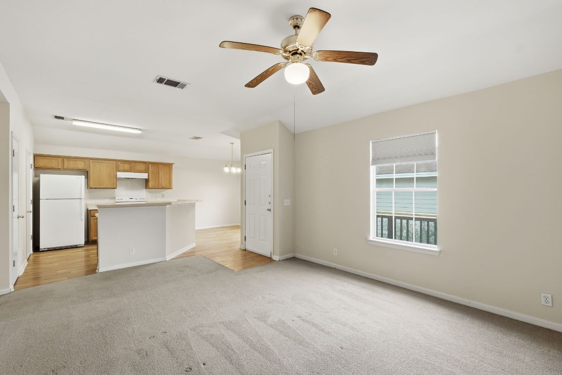 3201 E El Salido Parkway, Unit 511 Cedar Park, TX 78613 - Photo 2 of 12 Unfurnished living room with light carpet, ceiling fan, and a chandelier