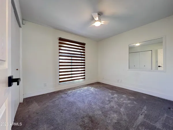 an empty room with windows and fan