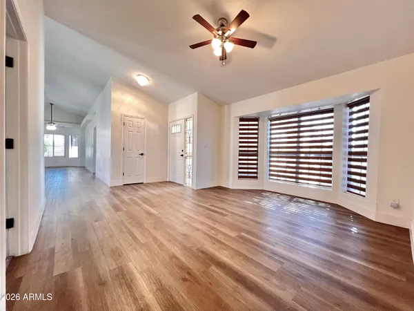 a view of an empty room with wooden floor and a window