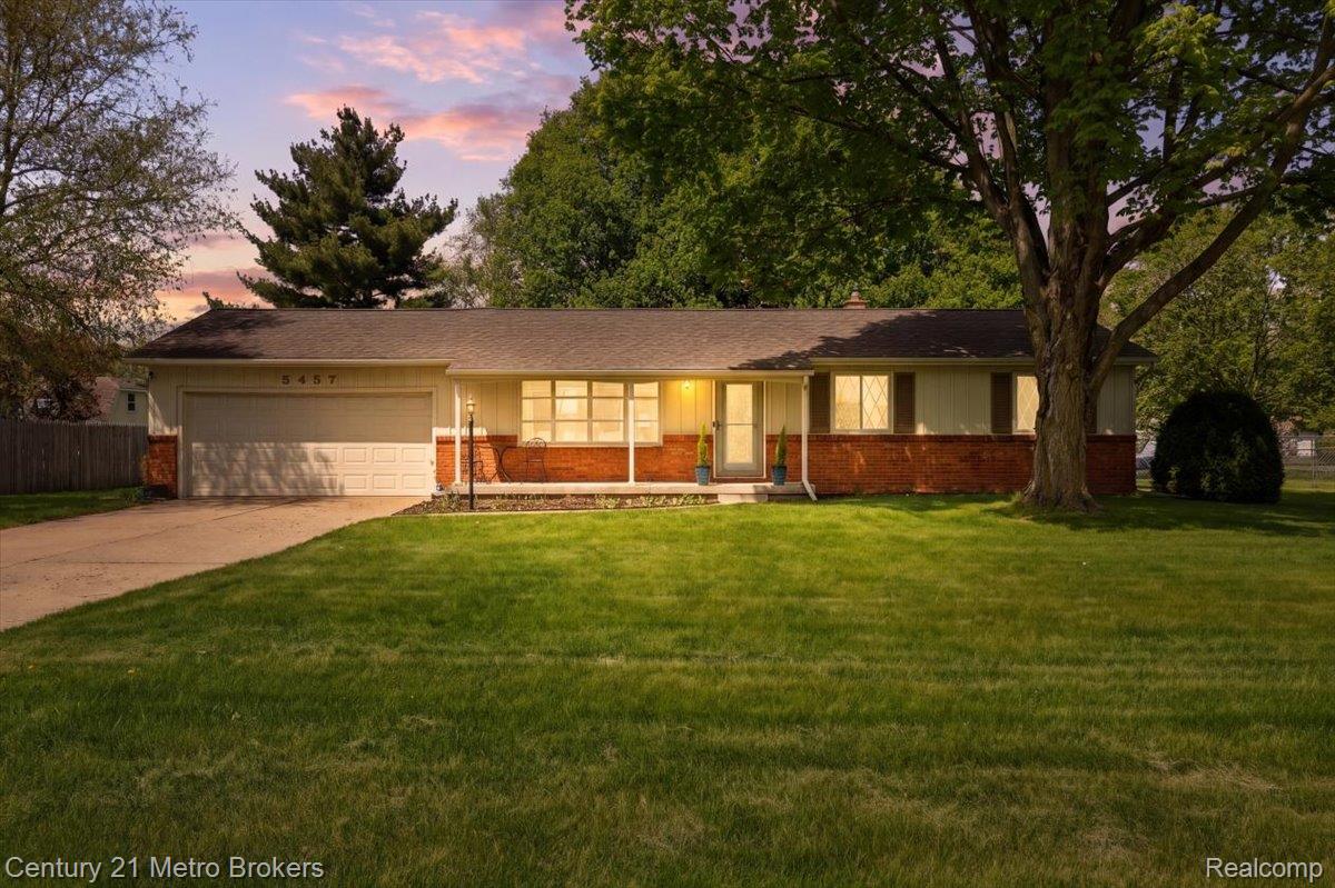 Ranch-style home with an attached garage, concrete driveway, brick siding, and a front yard
