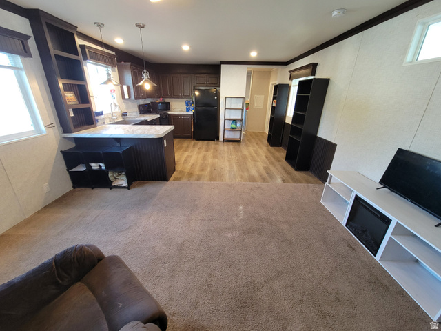 156 Cushing Way Layton, UT 84041 - Photo 6 of 20 Open-concept living space featuring wood-finish flooring, a kitchen with dark cabinetry, and a breakfast bar with an integrated shelving unit