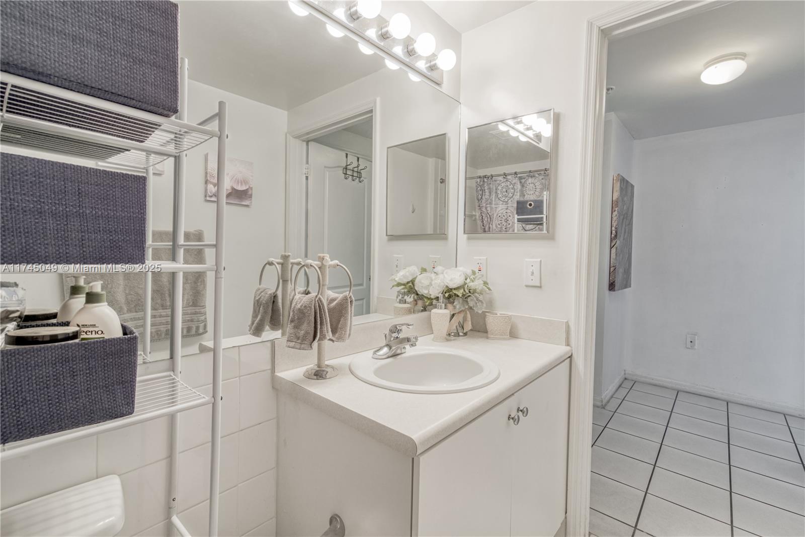 5091 Northwest 7th Street, Unit 1001 Miami, FL 33126 - Photo 11 of 17 a bathroom with a sink and a mirror