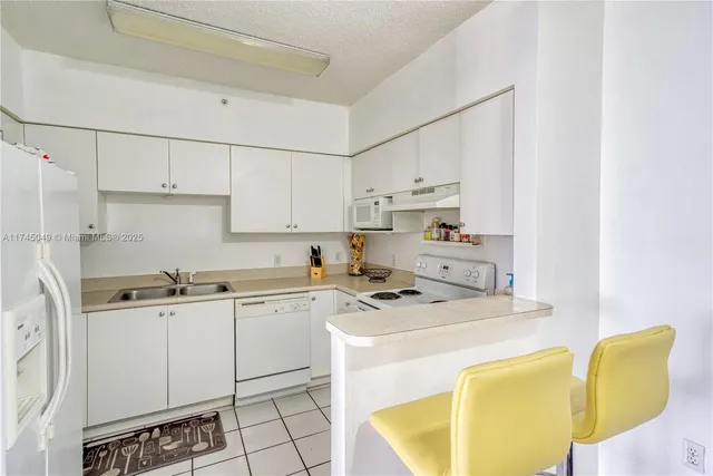 a kitchen with a sink a stove a refrigerator and white cabinets
