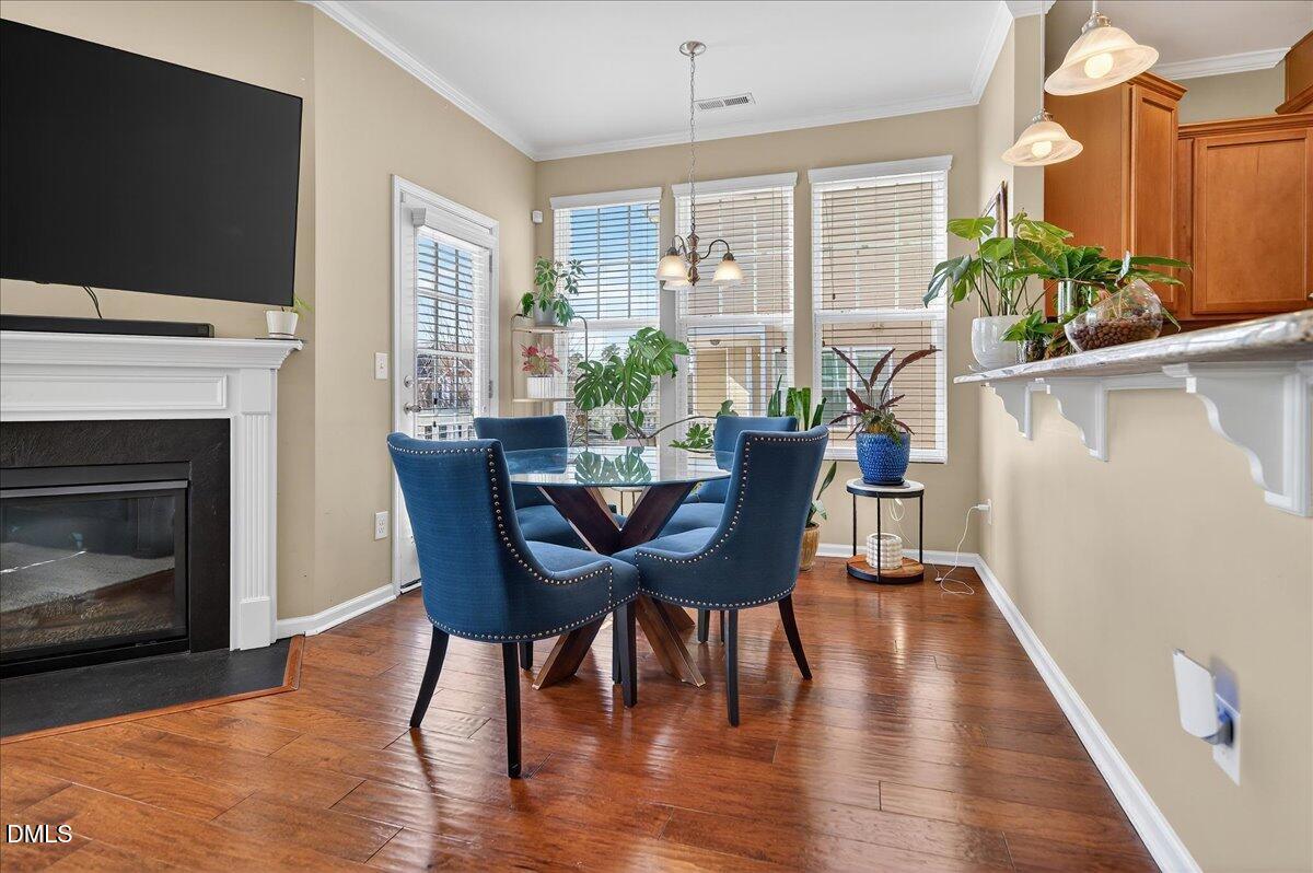 9328 Wooden Road Raleigh, NC 27617 - Photo 21 of 58 a dining room with furniture potted plants and wooden floor