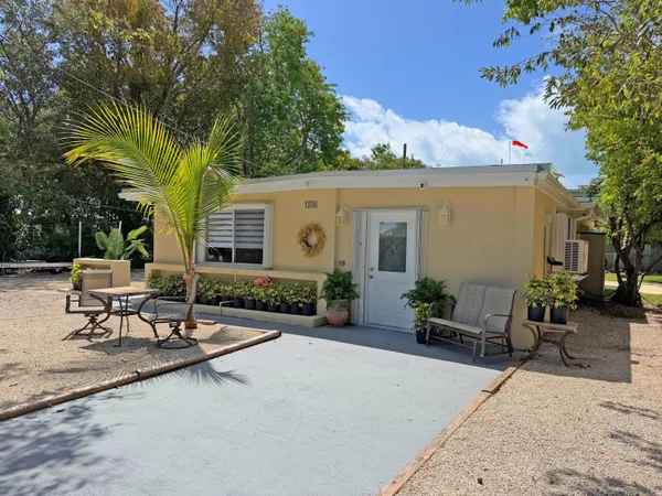 a view of a patio with table and chairs potted plants and a large tree