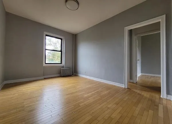 a view of an empty room with window and wooden floor