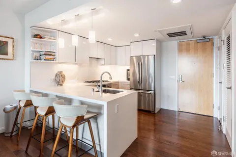 a kitchen with stainless steel appliances a refrigerator a sink dishwasher a stove and a refrigerator with wooden floor