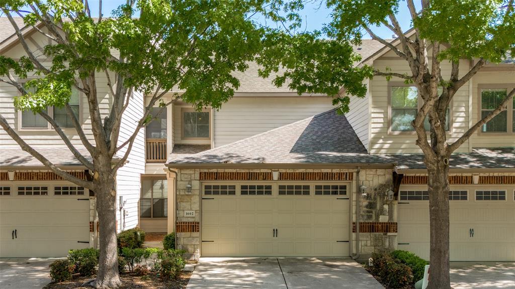 View of property with roof with shingles, concrete driveway, and stone siding