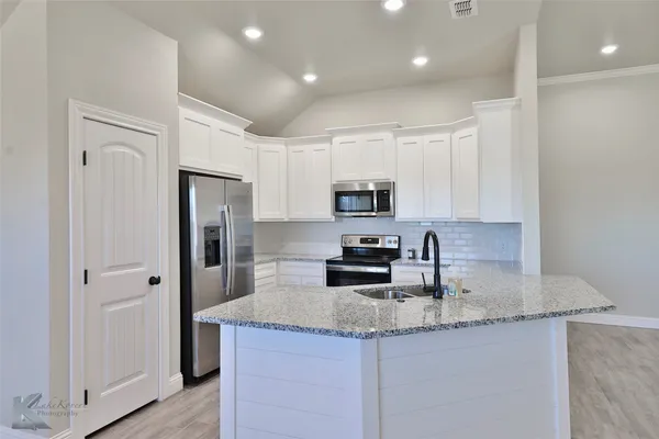 a kitchen with stainless steel appliances granite countertop a sink a refrigerator and a granite counter tops