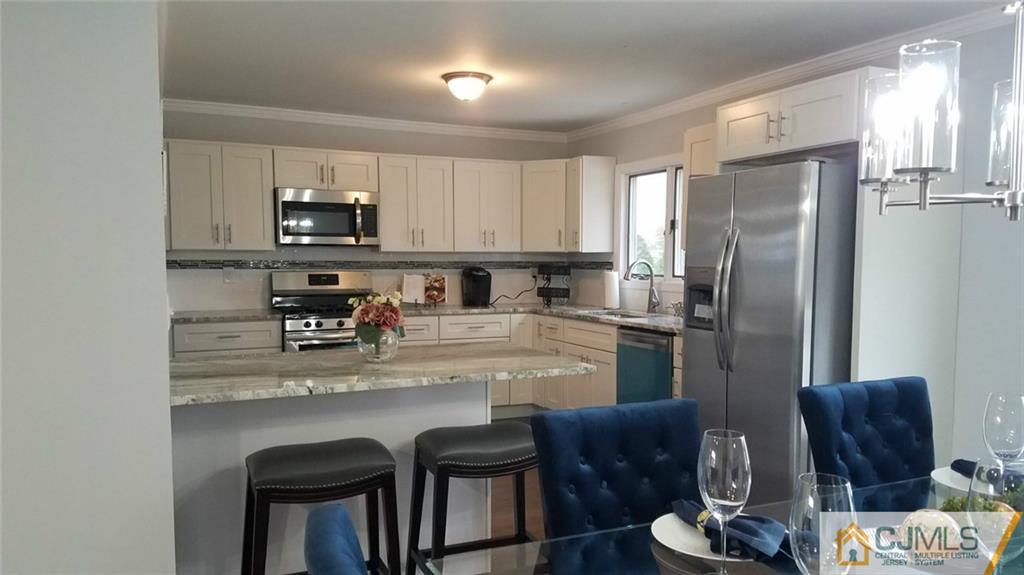 23 Ferris Road Edison, NJ 08817 - Photo 7 of 21 a kitchen with stainless steel appliances granite countertop a refrigerator a sink a stove a dining table and chairs with wooden floor