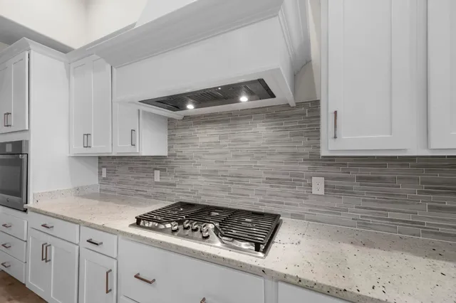 a large kitchen with kitchen island a sink a stove a refrigerator and white cabinets