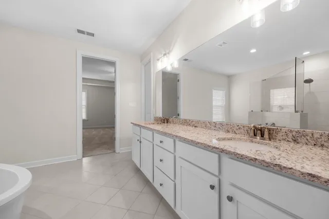 a bathroom with a granite countertop sink two mirror and a bathtub