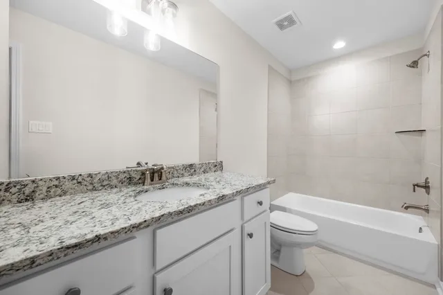 a bathroom with a granite countertop sink a toilet and shower