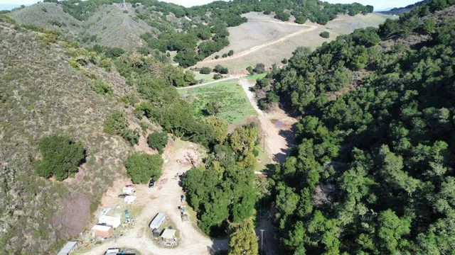 an aerial view of residential house with outdoor space and trees all around