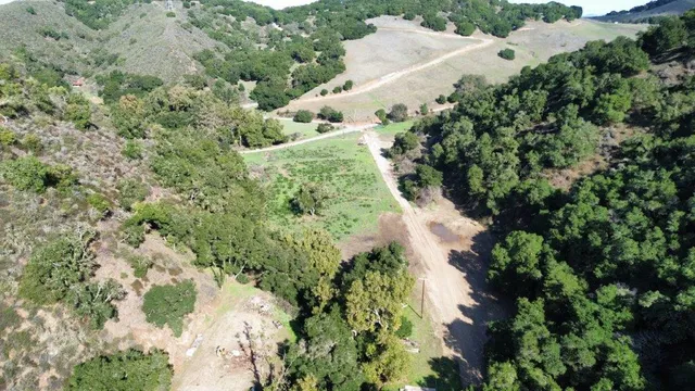 an aerial view of residential house with outdoor space and trees all around
