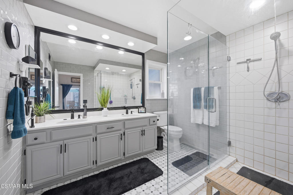 2497 Orangewood Place Simi Valley, CA 93065 - Photo 21 of 42 a bathroom with a double vanity sink a toilet a mirror and shower