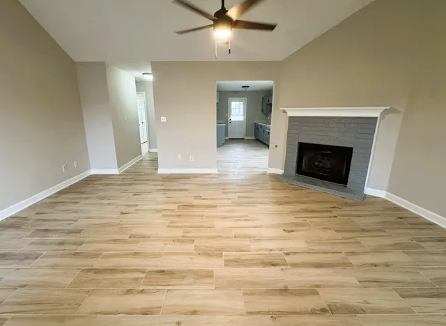a view of an empty room with wooden floor and a fireplace