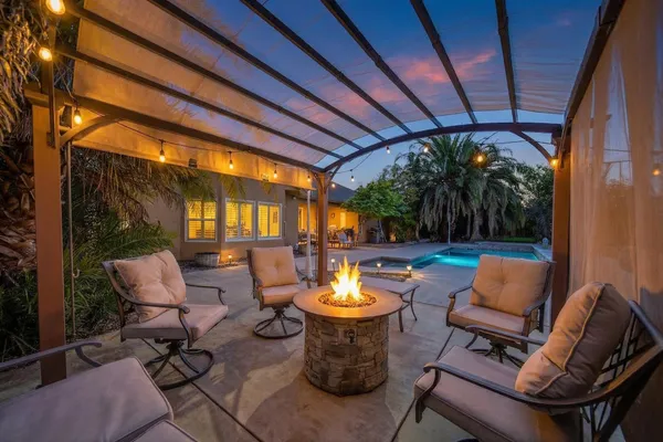 a view of a chairs and table in the patio next to a yard