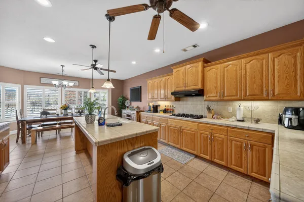 a kitchen with a stove a sink a kitchen island with chairs and wooden cabinets