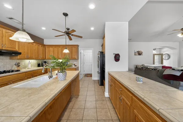 a large kitchen with stainless steel appliances a large counter top a stove a chimney a sink and a refrigerator
