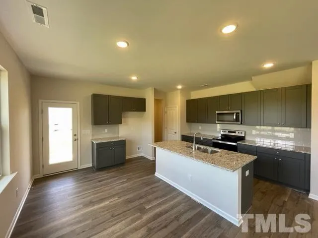 a kitchen with stainless steel appliances a stove top oven a sink a refrigerator and white cabinets