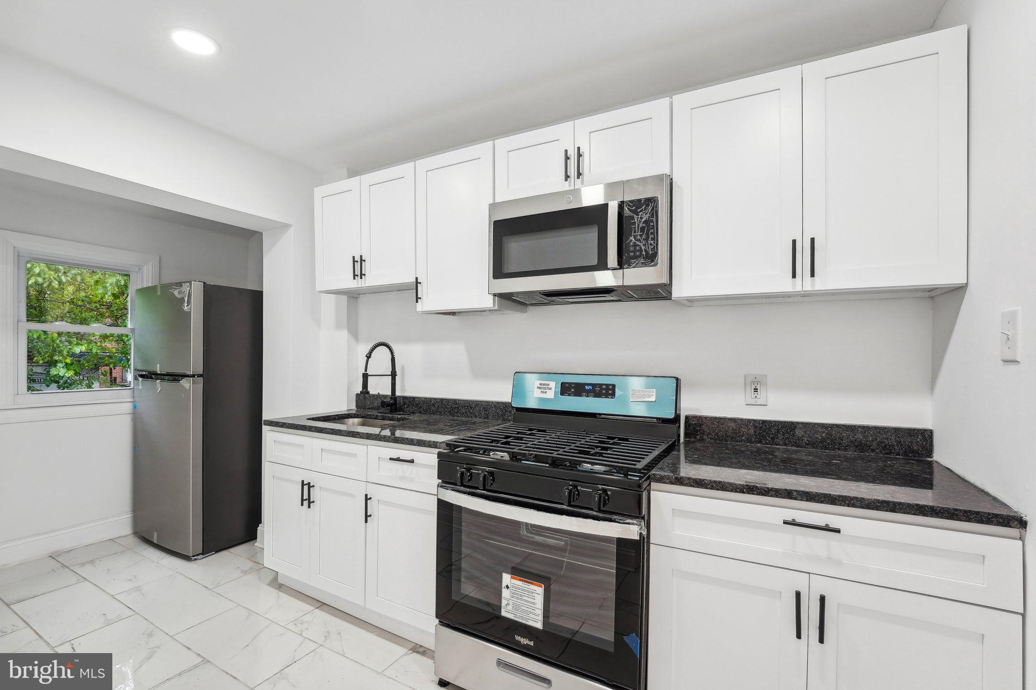 a kitchen with stainless steel appliances granite countertop white cabinets a stove a sink and dishwasher